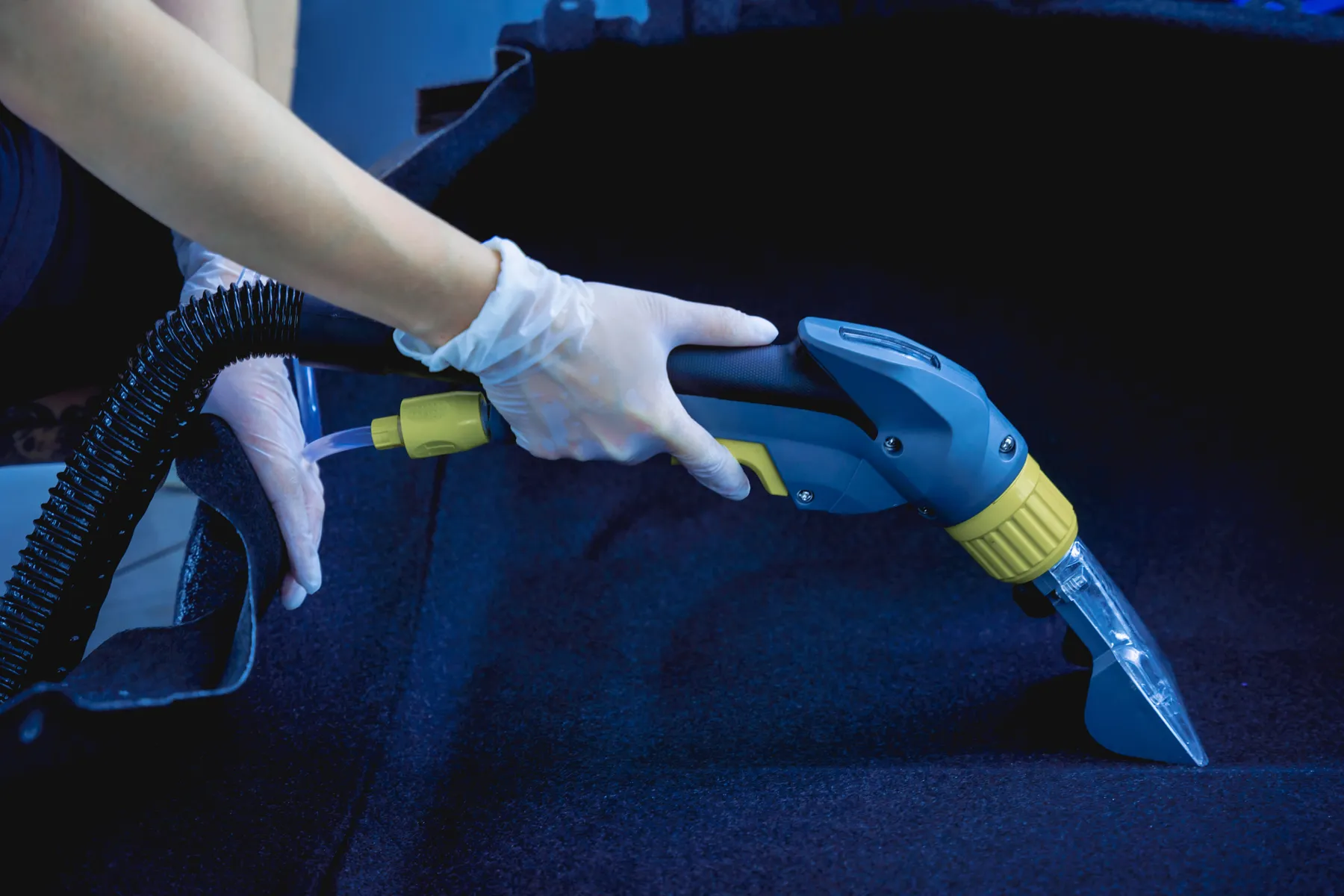 Detailer extracting dirt from SUV carpet