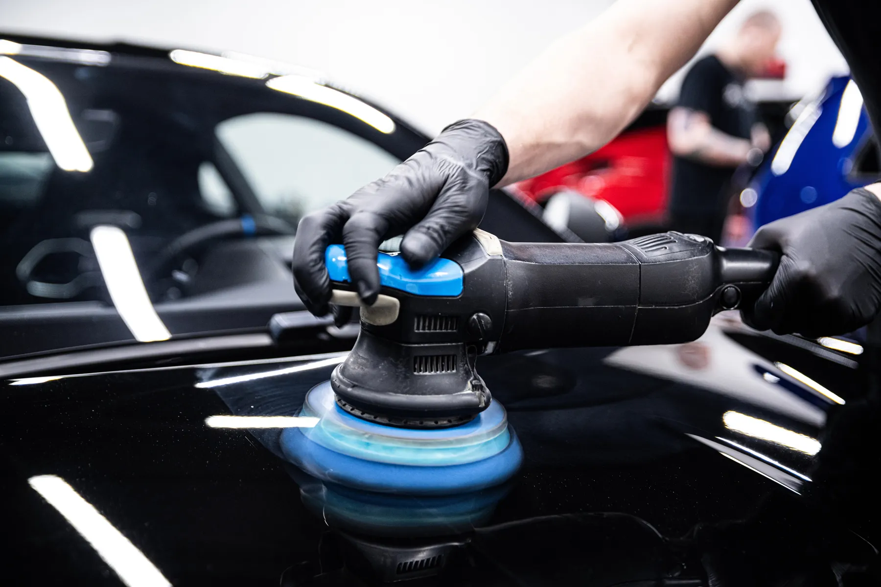 Dual-action polisher removing swirl marks from black paint