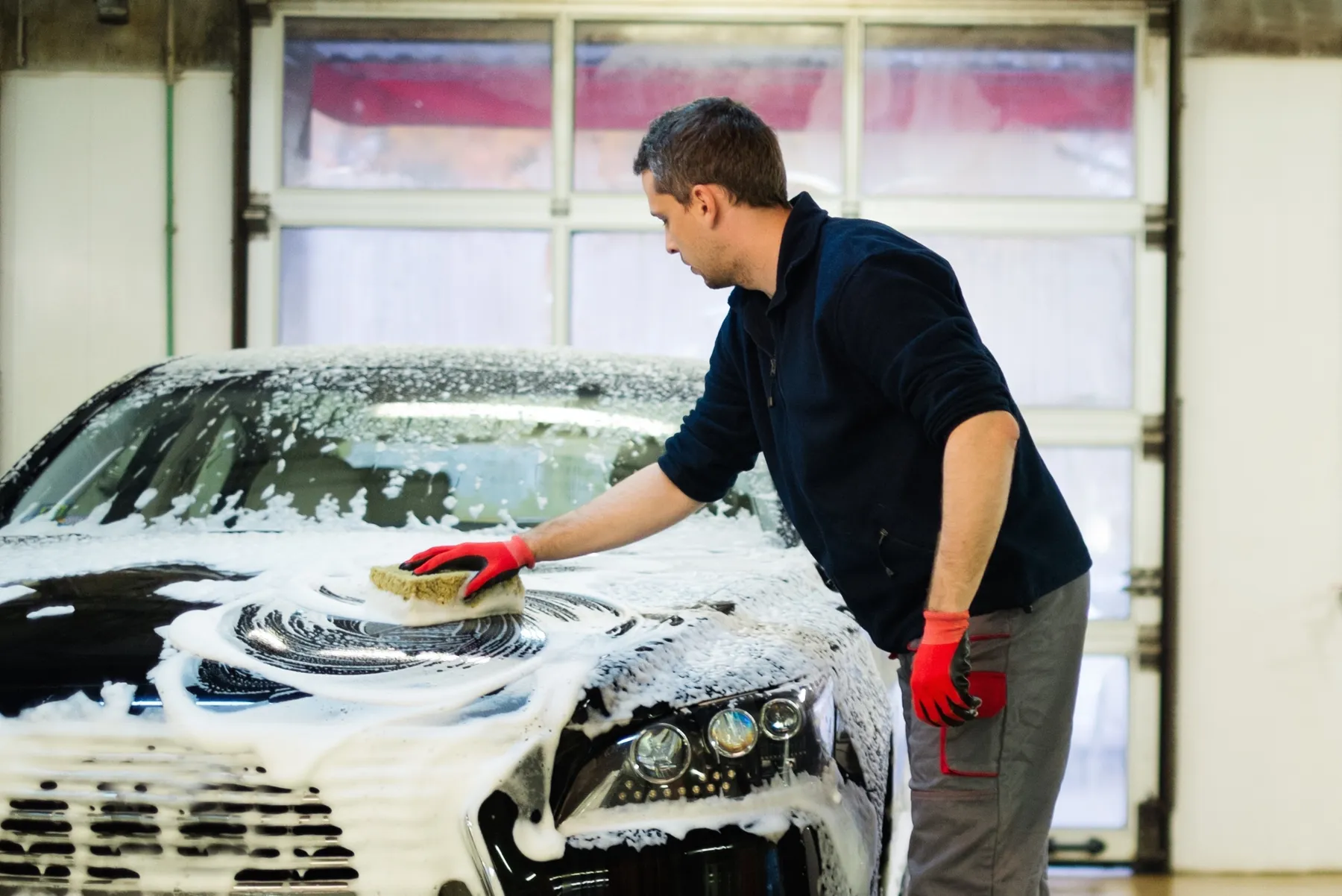 Detailer washing a foam-covered car with a wash pad