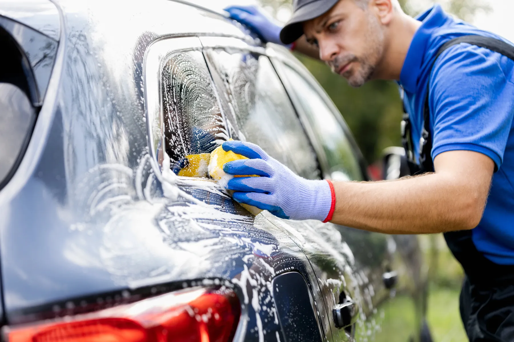 Gifted Hands detailer hand-washing a car with a sponge and soap